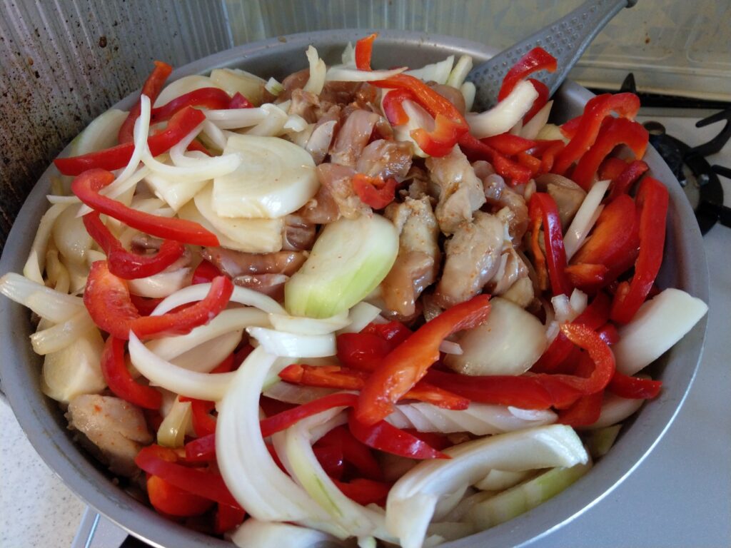 フライパンで野菜と鶏もも肉を炒めている